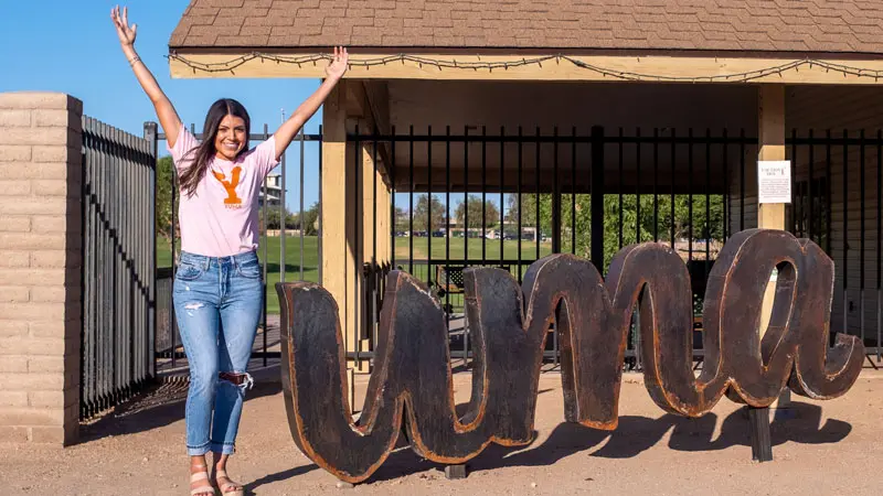 A woman poses as the letter Y in front of the uma sign at the Colorado River State Historic Park